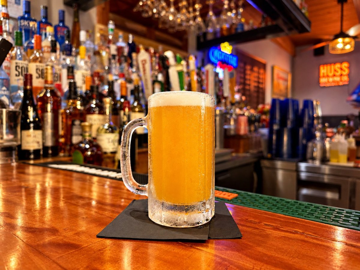 Foamy mug of golden beer on a bar counter with bottles and neon signs in the background